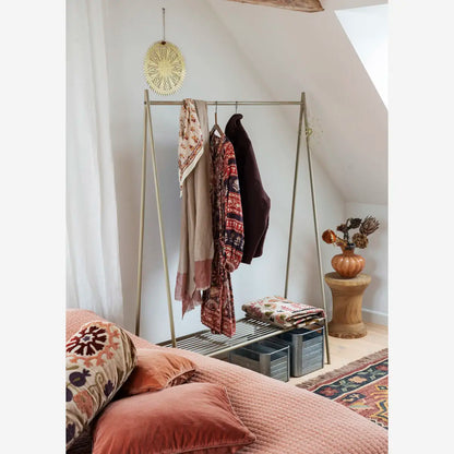 Madam Stoltz Velvet Cushion Covers in coral pink and embroidered patterns on a bed with a clothes rack.