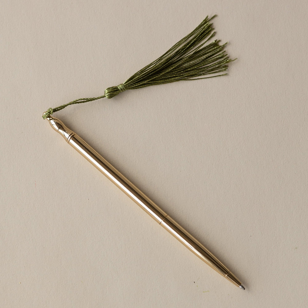 24k Gold Plated Ballpoint Pen by Roomytown, golden pen with a green tassel on a light background.