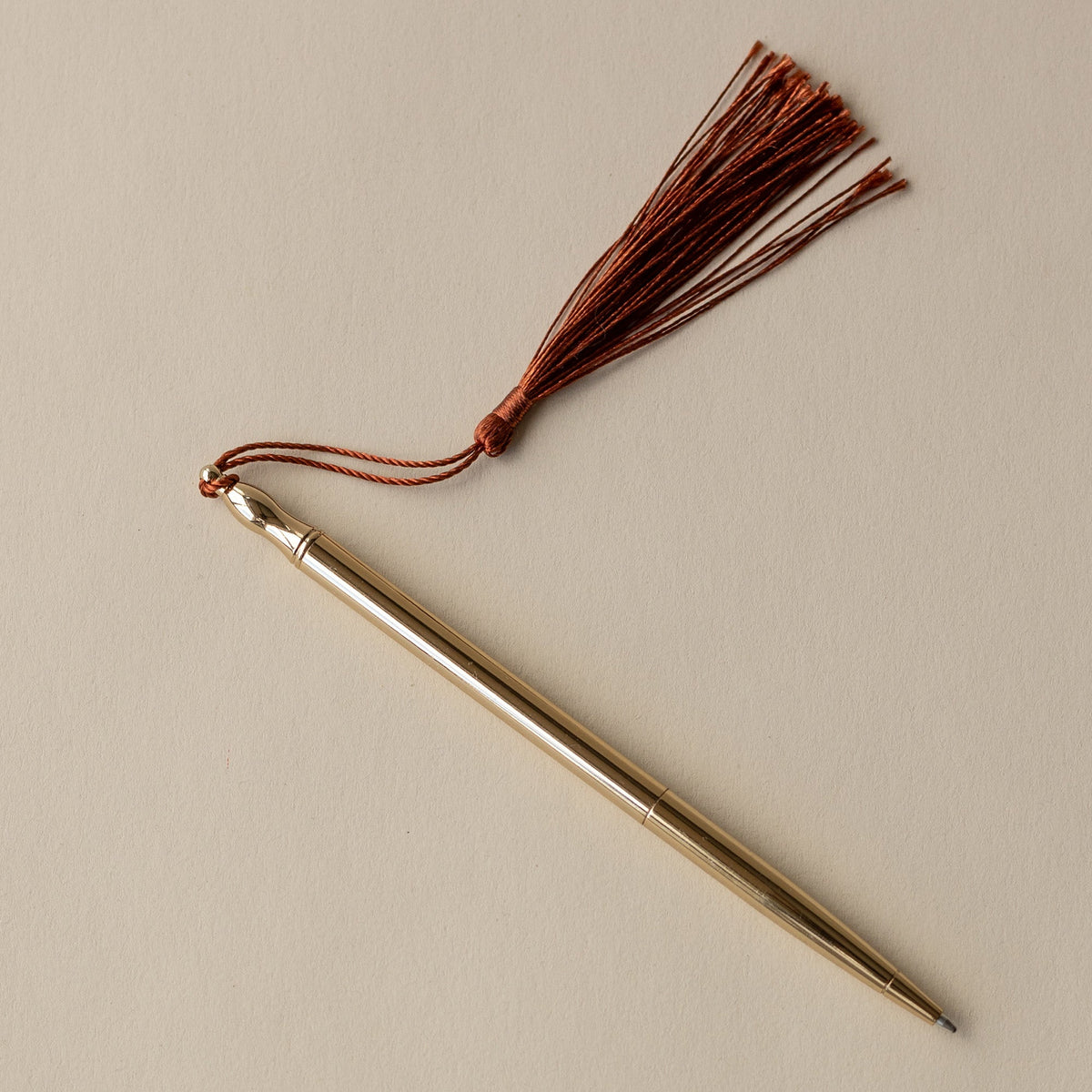 Roomytown 24k Gold Plated Ballpoint Pen with a brown tassel on a light background.