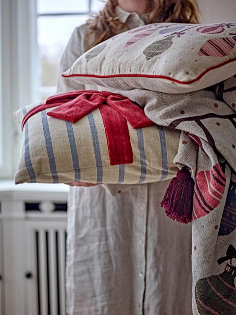 Bloomingville Ornamentia Throw, Red, with festive Christmas ornament pattern and tassel, held by a person with matching pillows.