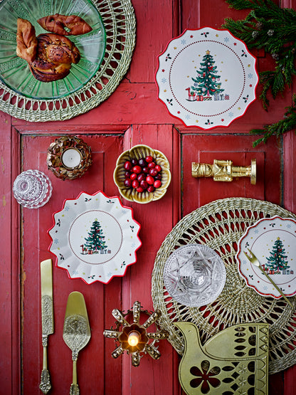 Bloomingville Naive festive flat lay: red-edged Christmas plates, cranberry bowl, gold cutlery, pastries on woven mats &amp; red wood.