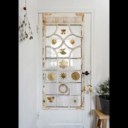 Madam Stoltz Hanging Brass Bow on a distressed white glass door with other gold Christmas decorations.
