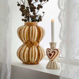 Madam Stoltz hand-painted candle holder with heart design, displayed next to a vase on a sunlit windowsill.