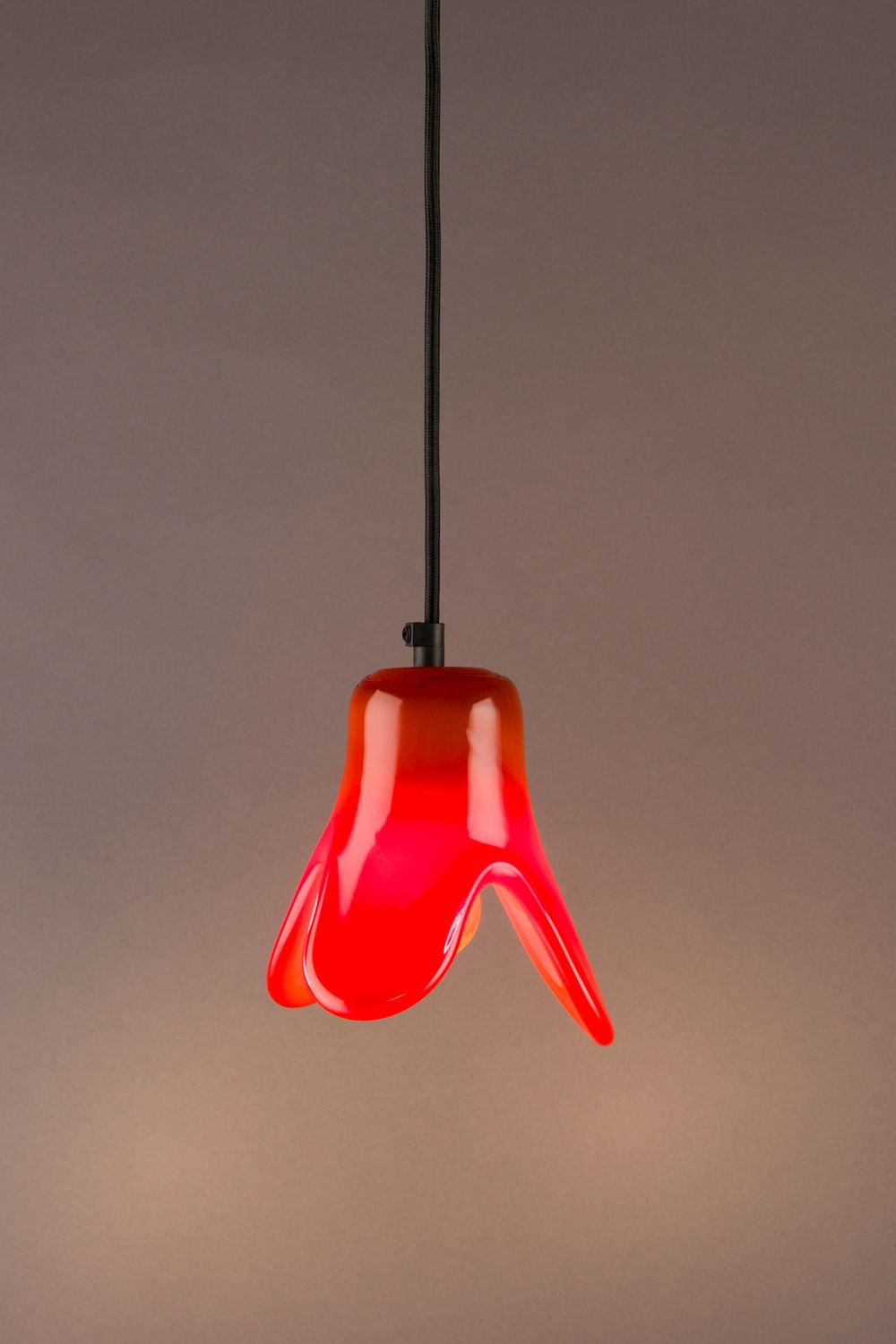 Dutchbone Gable pendant lamp, a vibrant red and orange glass fixture with an organic, wavy shape, hanging from a black cord.
